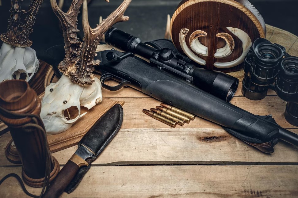 a knife, deer skulls, a binocular, and a rifle with a muzzleloader scope