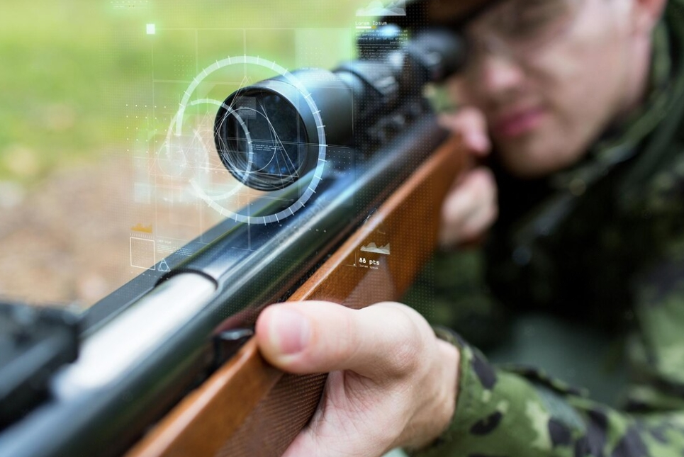 man in military clothing holding gun and watching on the scope