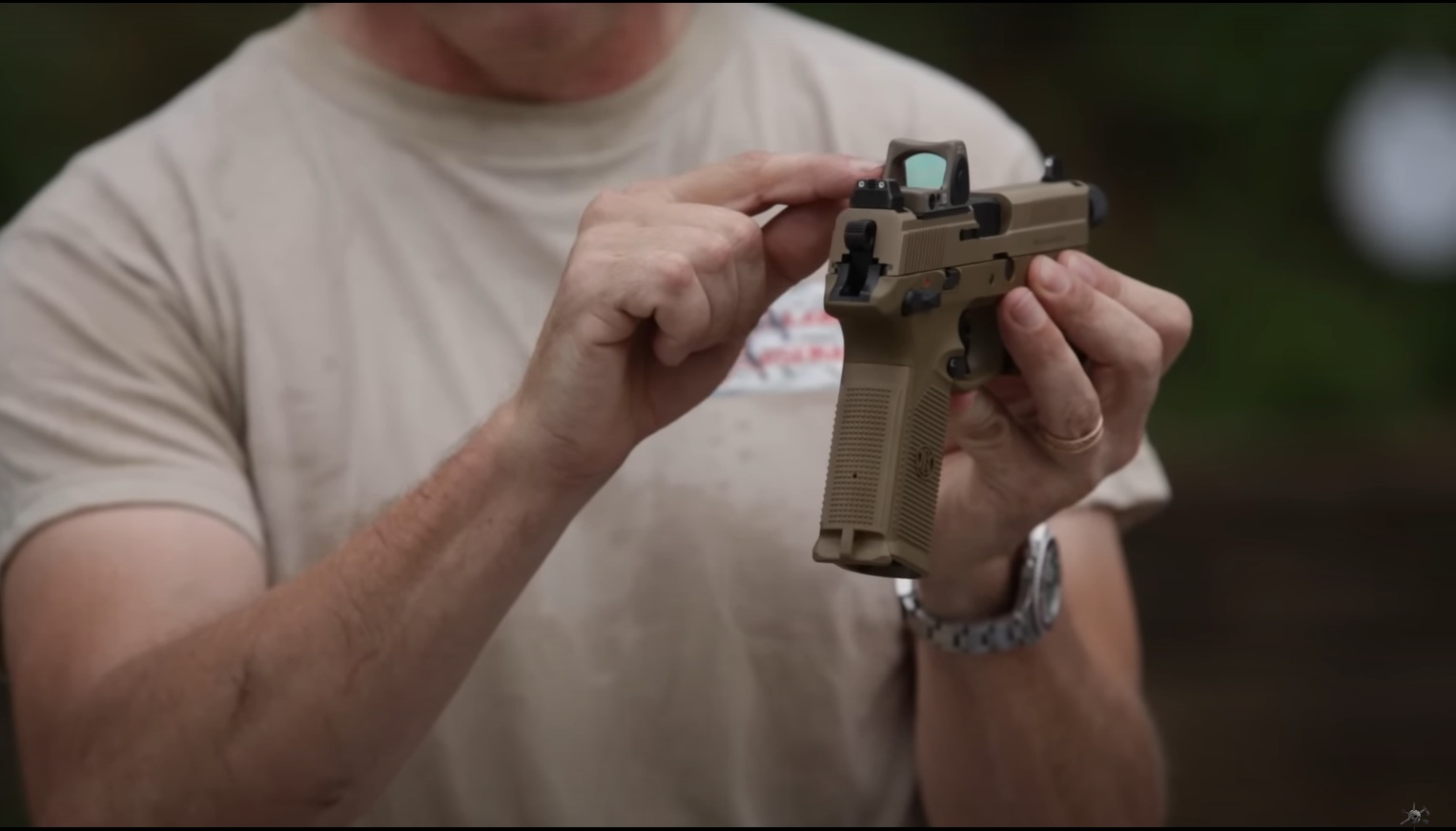 A man holds a pistol in his hands and points to a collimator sight